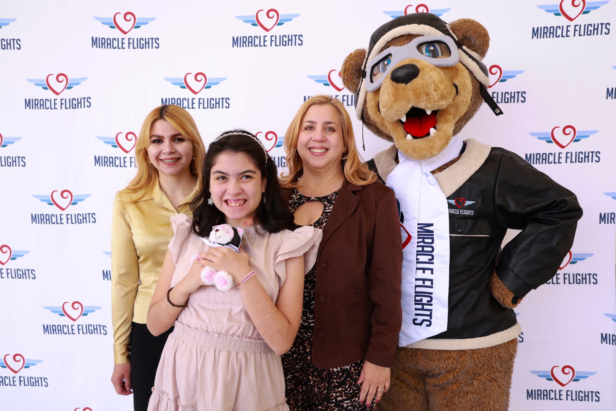 Smiling family posing with Miracle Flights' mascot