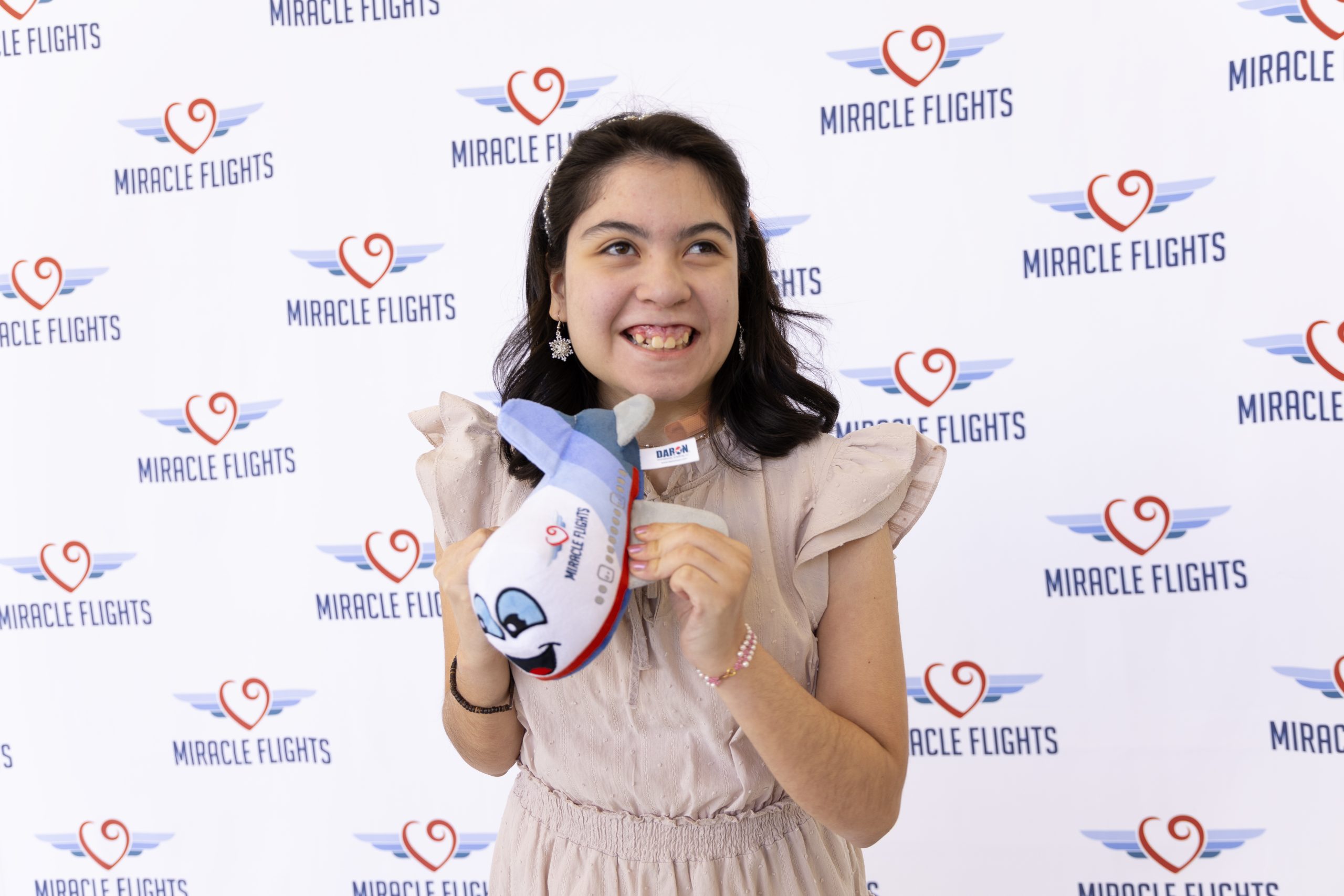 Smiling girl holding a Miracle Flights' stuffed airplane