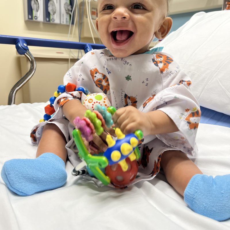 Happy baby playing with a toy on a hospital bed