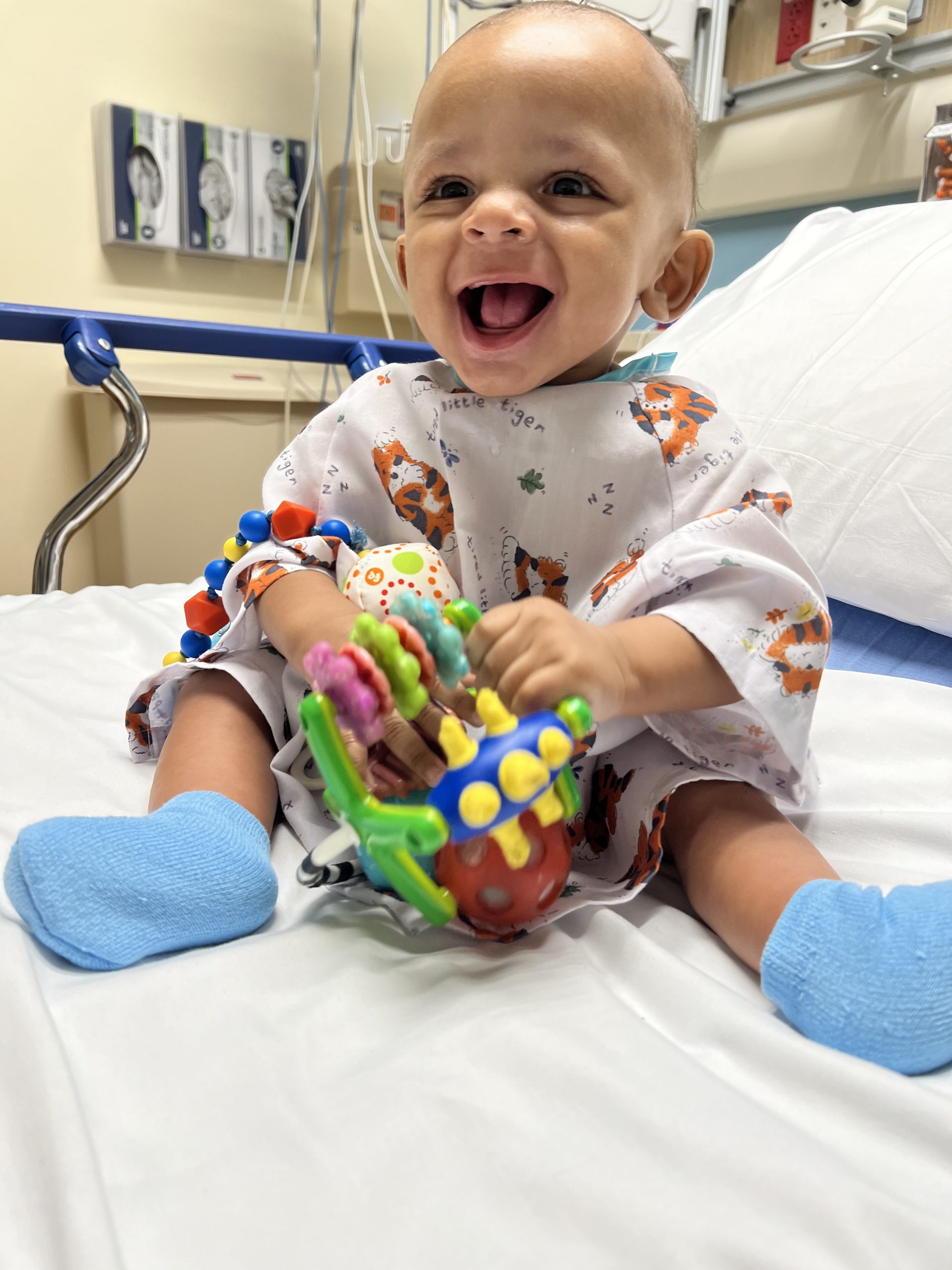 Happy baby playing with a toy on a hospital bed