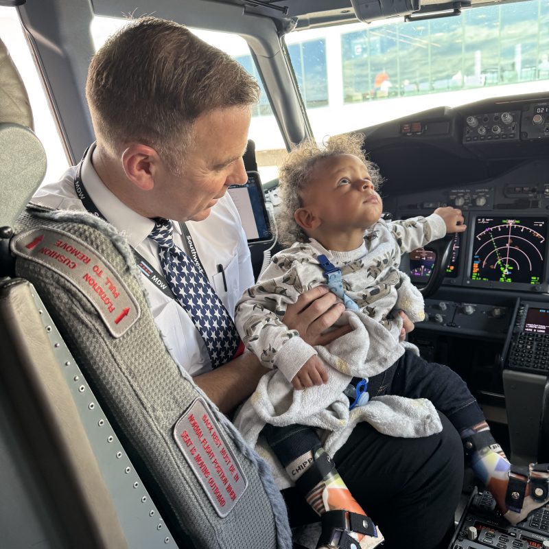 Pilot holding a baby girl, on the front of an airplane
