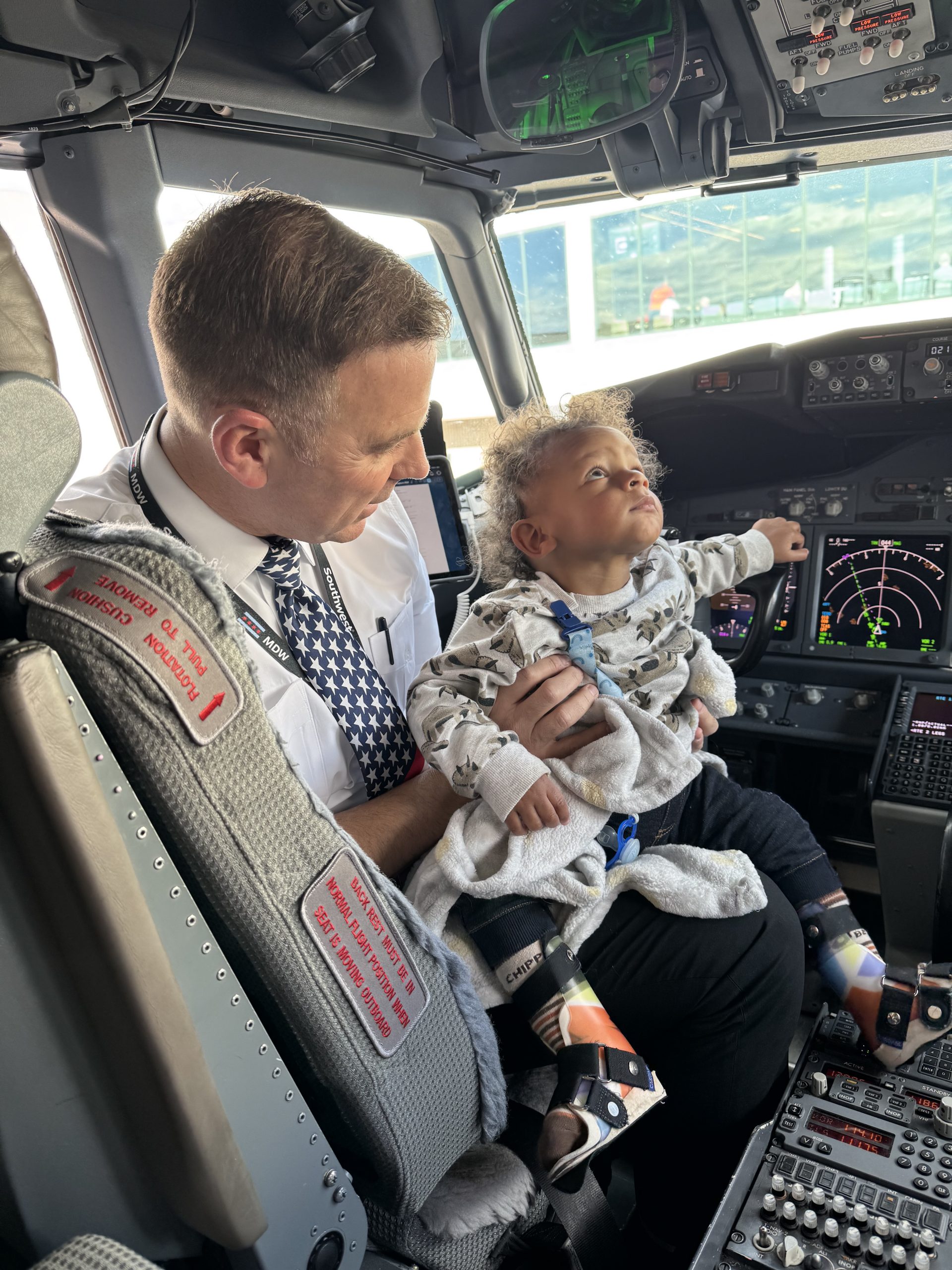 Pilot holding a baby girl, on the front of an airplane