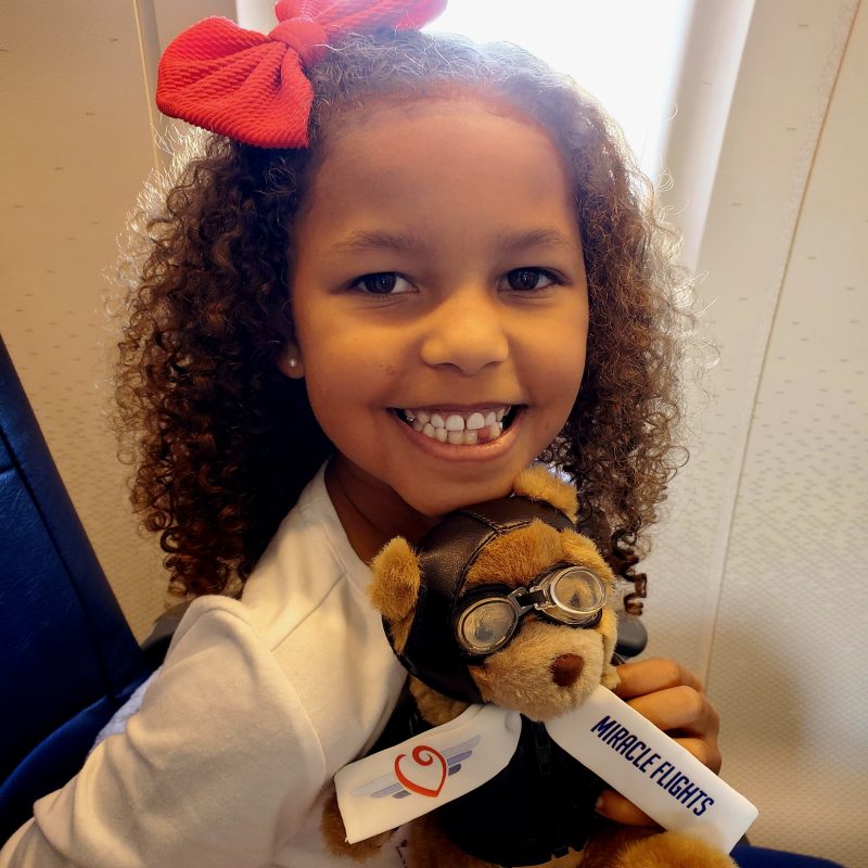 Smiling girl with a teddy bear and red bow