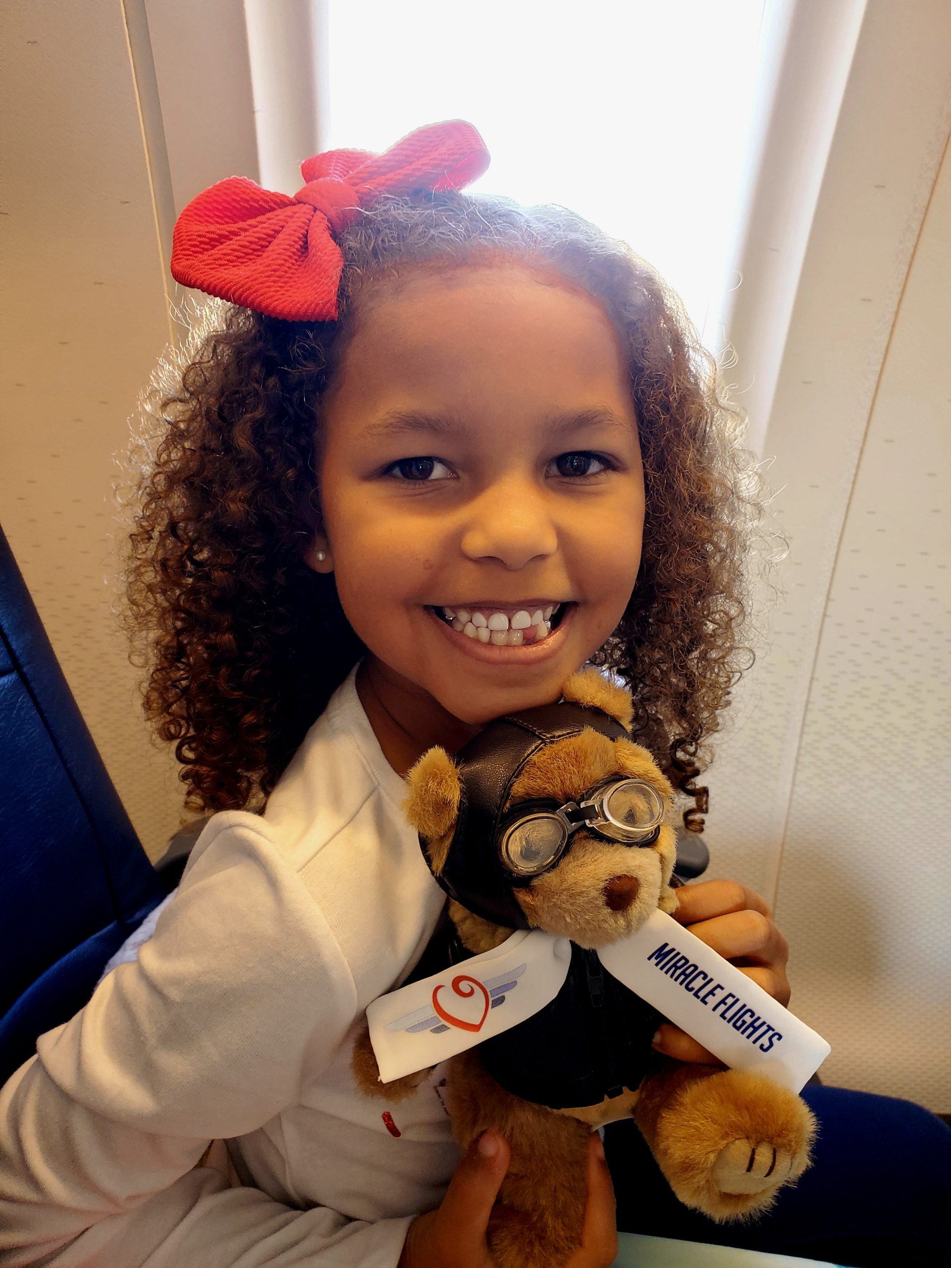 Smiling girl with a teddy bear and red bow