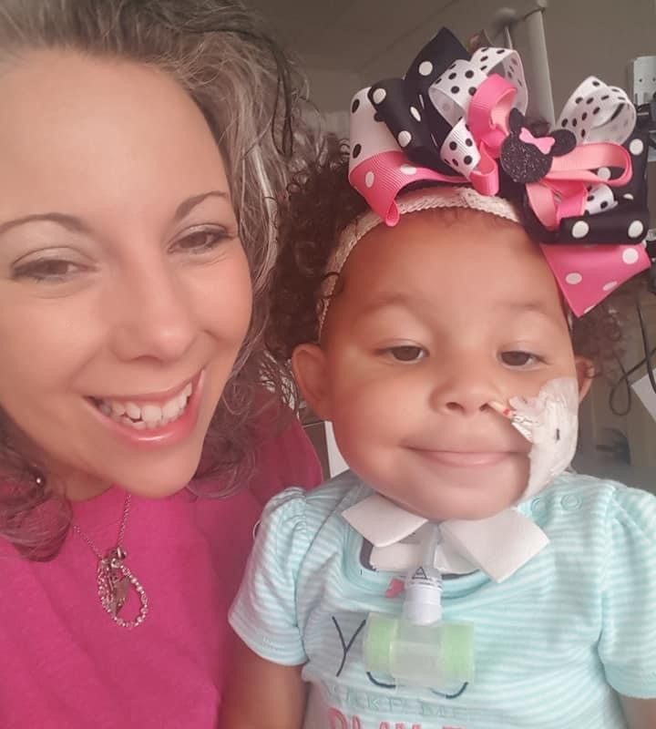 Smiling woman next to a young girl with medical equipment