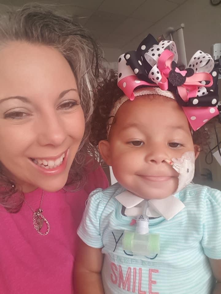 Smiling woman next to a young girl with medical equipment