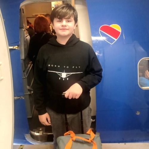 Boy outside an airplane, with his suitcase
