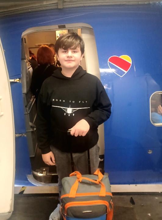 Boy outside an airplane, with his suitcase