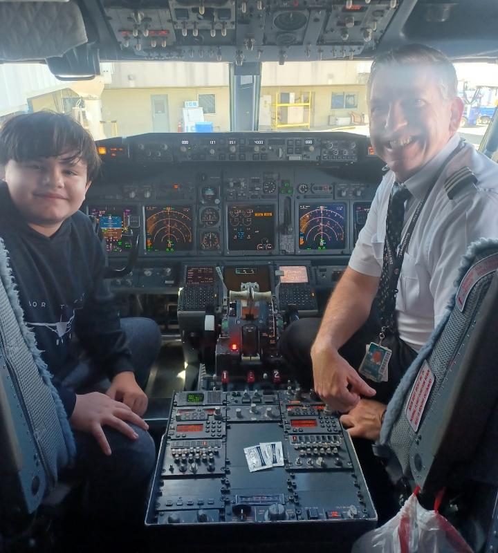 Smiling pilot and boy on the front of an airplane