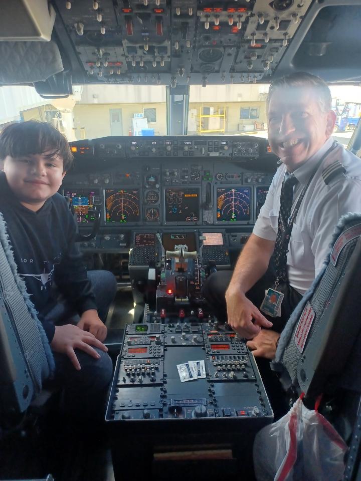 Smiling pilot and boy on the front of an airplane